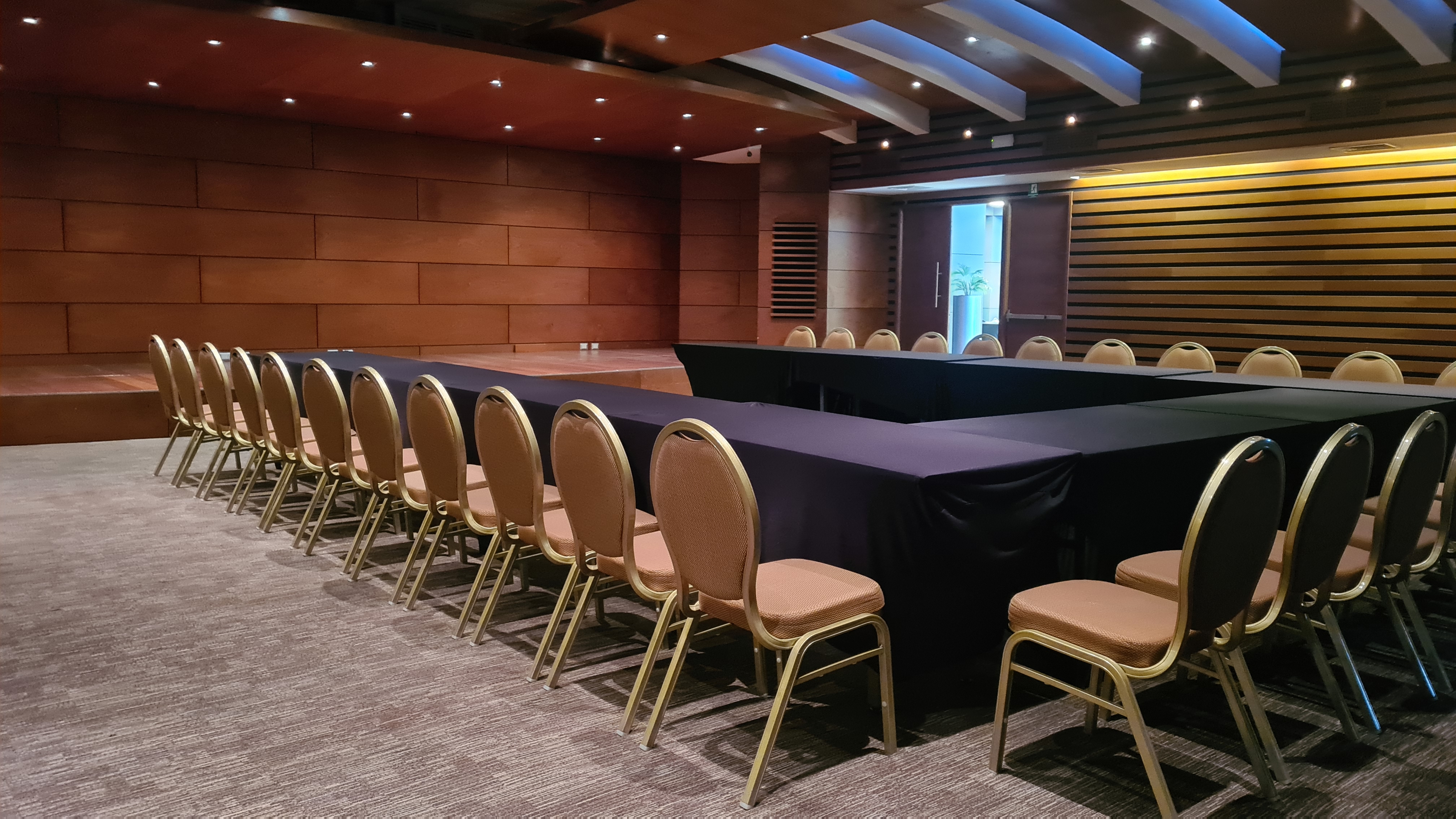 Auditorio Cowork V21 con escenario, mesas y sillas para eventos